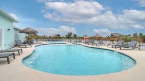 A swimming pool with lounge chairs and a thatched-roof structure. - 34 Sailfish RV Resort, Port Aransas RV Getaway (Port Aransas)