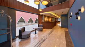 A modern hotel lobby with a reception desk, seating area, and large windows. - Rest by Dedeman Karabuk (Karabük)