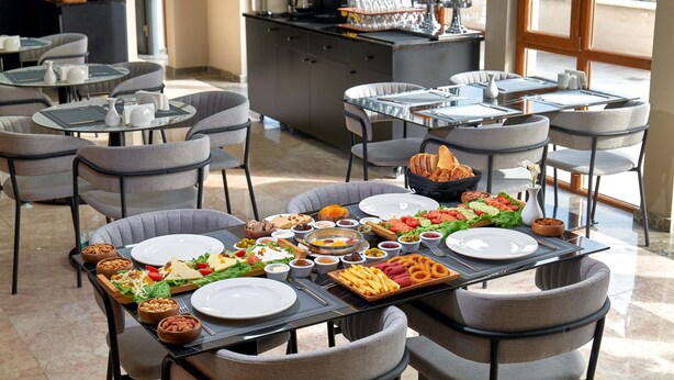 A dining area with multiple tables set for meals, including plates, bowls, and various food items. - Rest by Dedeman Karabuk (Karabük)