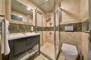 Un baño moderno con cabina de ducha de vidrio, inodoro blanco y tocador con espejo.