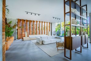 A modern living room with a sectional sofa, a wooden accent wall, and a view of greenery outside.