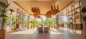 A spacious indoor area with a dining table and chairs, surrounded by shelves with various items. - Casa Maya | 1-BR Oasis in Romantic Zone (Puerto Vallarta)