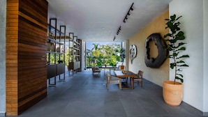 A modern interior with a wooden partition, a dining area with chairs and a table, and a large potted plant.