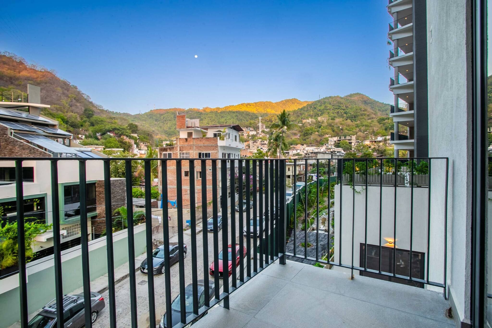 The bedroom's balcony overlooks a serene street with a backdrop of majestic mountains