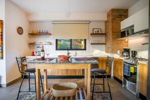 Una cucina moderna con zona pranzo, che include un tavolo di legno, sedie, un'ampia finestra ed elettrodomestici a incasso.