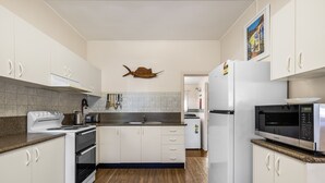 A modern kitchen with white cabinets, a microwave, an oven, and a sink.