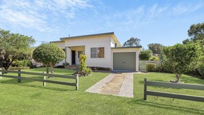 A modern two-story house with a garage, surrounded by a well-maintained lawn and a wooden fence.