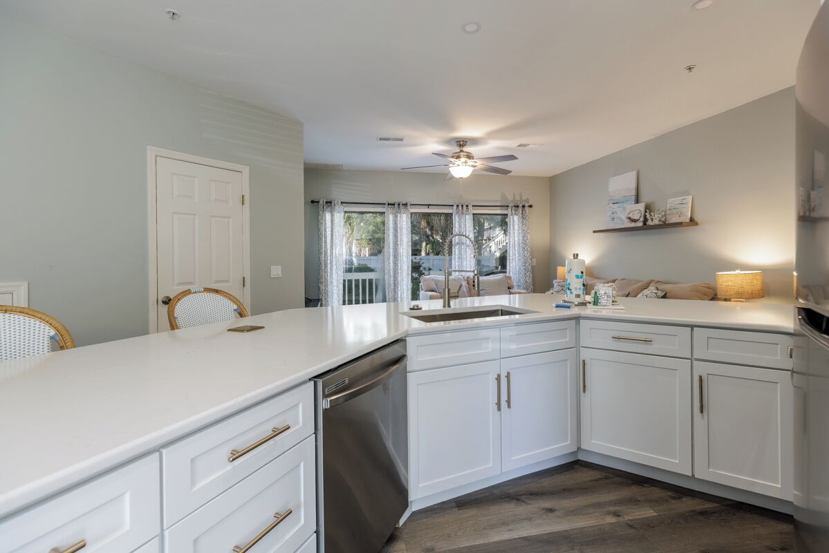 A modern kitchen with white cabinetry, a dishwasher, and a ceiling fan.