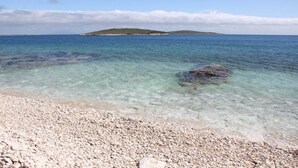 A pebble beach with clear water and a distant island. - OLIVA HOUSE BOAT - Unique Experience near Beaches, Amenities, Fun and History (Pula)