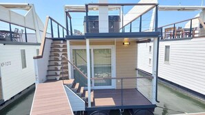 A multi-level boat with a wooden deck, glass railings, and a small enclosed area with a door. - OLIVA HOUSE BOAT - Unique Experience near Beaches, Amenities, Fun and History (Pula)
