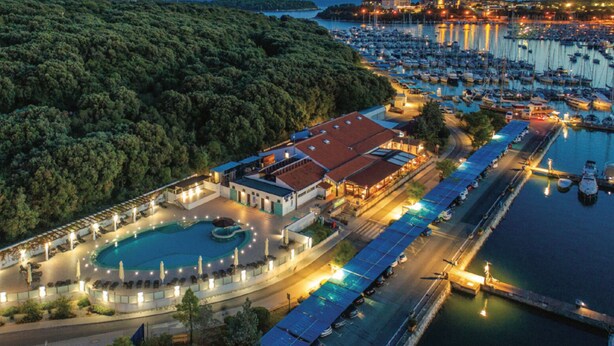 An aerial view of a resort with a swimming pool, a marina, and a forested hill. - OLIVA HOUSE BOAT - Unique Experience near Beaches, Amenities, Fun and History (Pula)