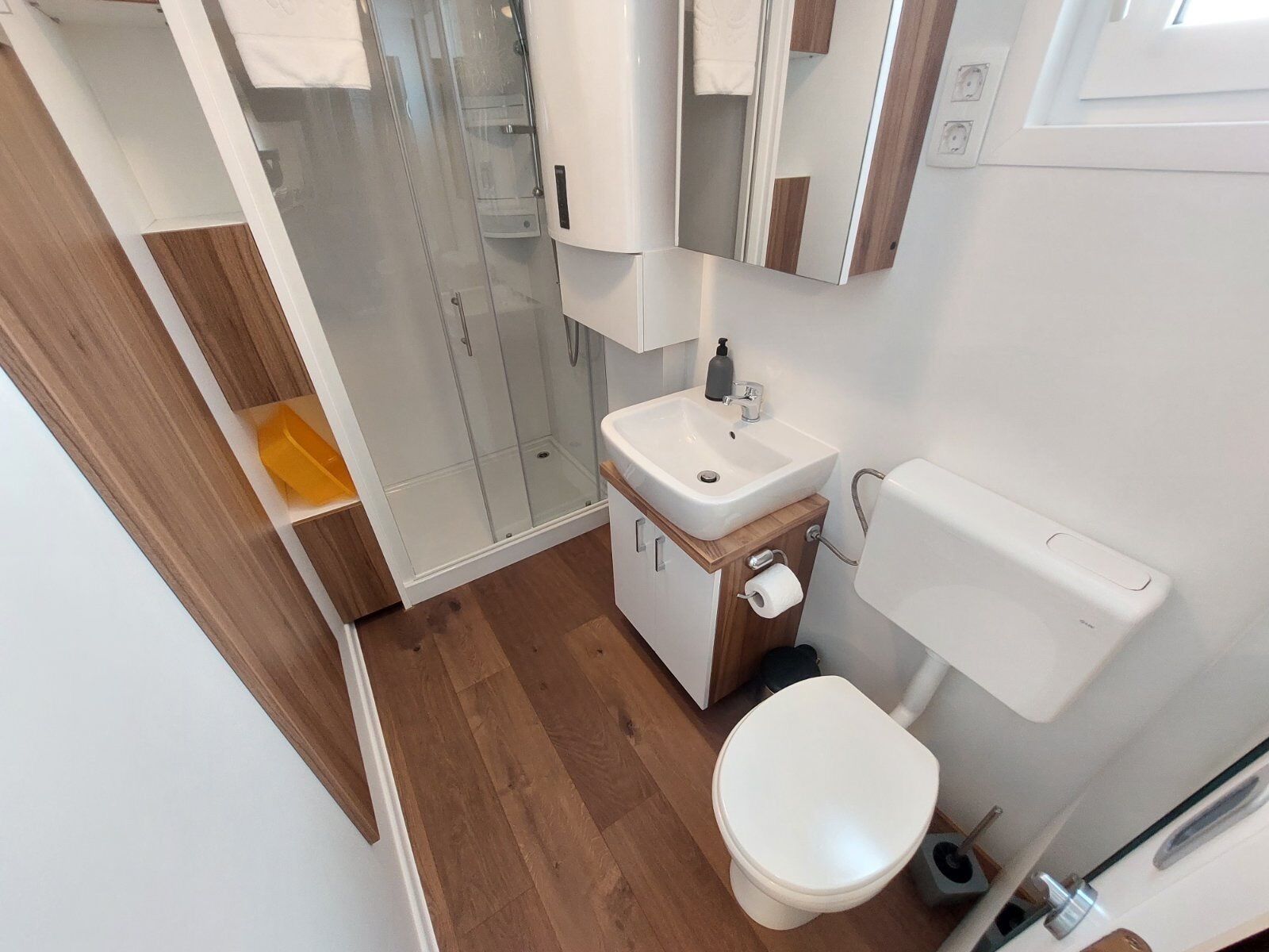 Ein modernes Badezimmer mit Duschkabine aus Glas, einem weißen Waschbecken und einer Toilette.