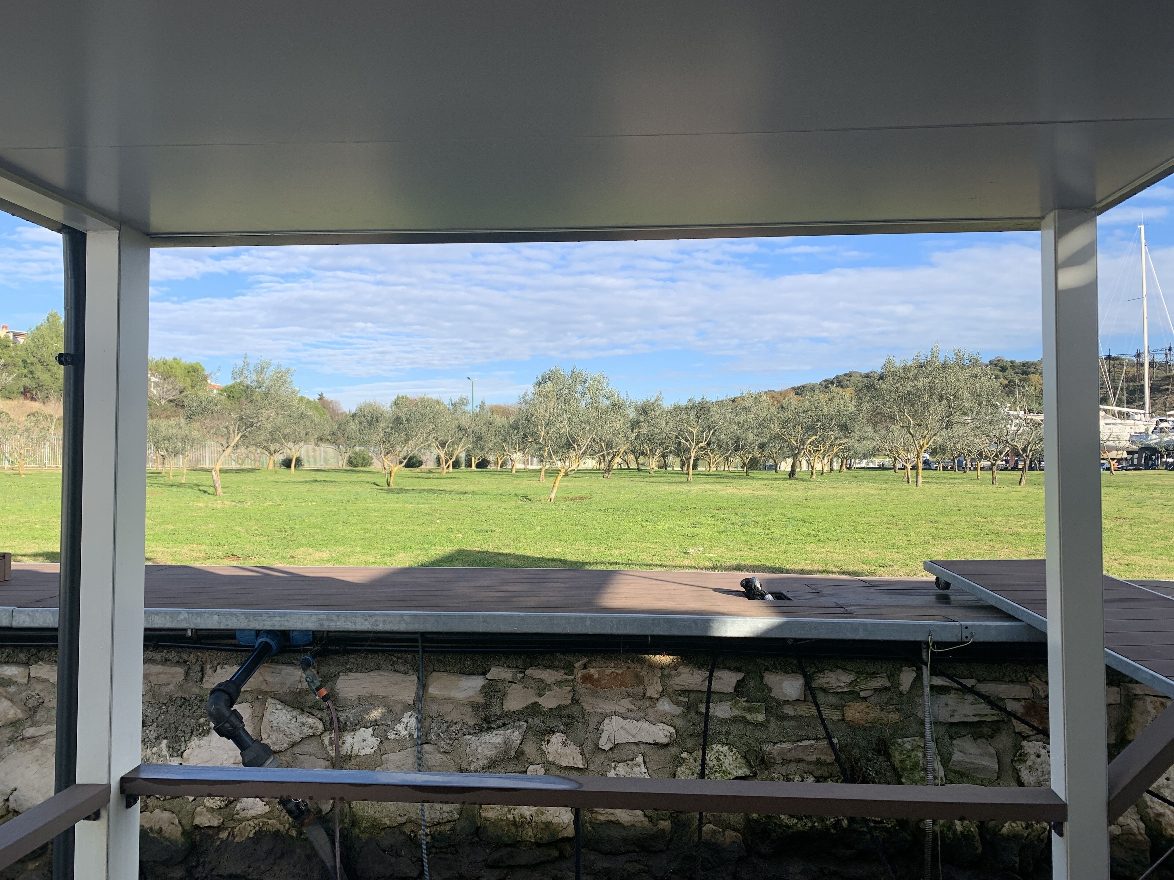 Une vue depuis un espace extérieur abrité, doté de murs en pierre et donnant sur un champ herbeux.