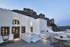 Terraza en la azotea con piscina, zona de estar y vistas a un muro de piedra histórico.