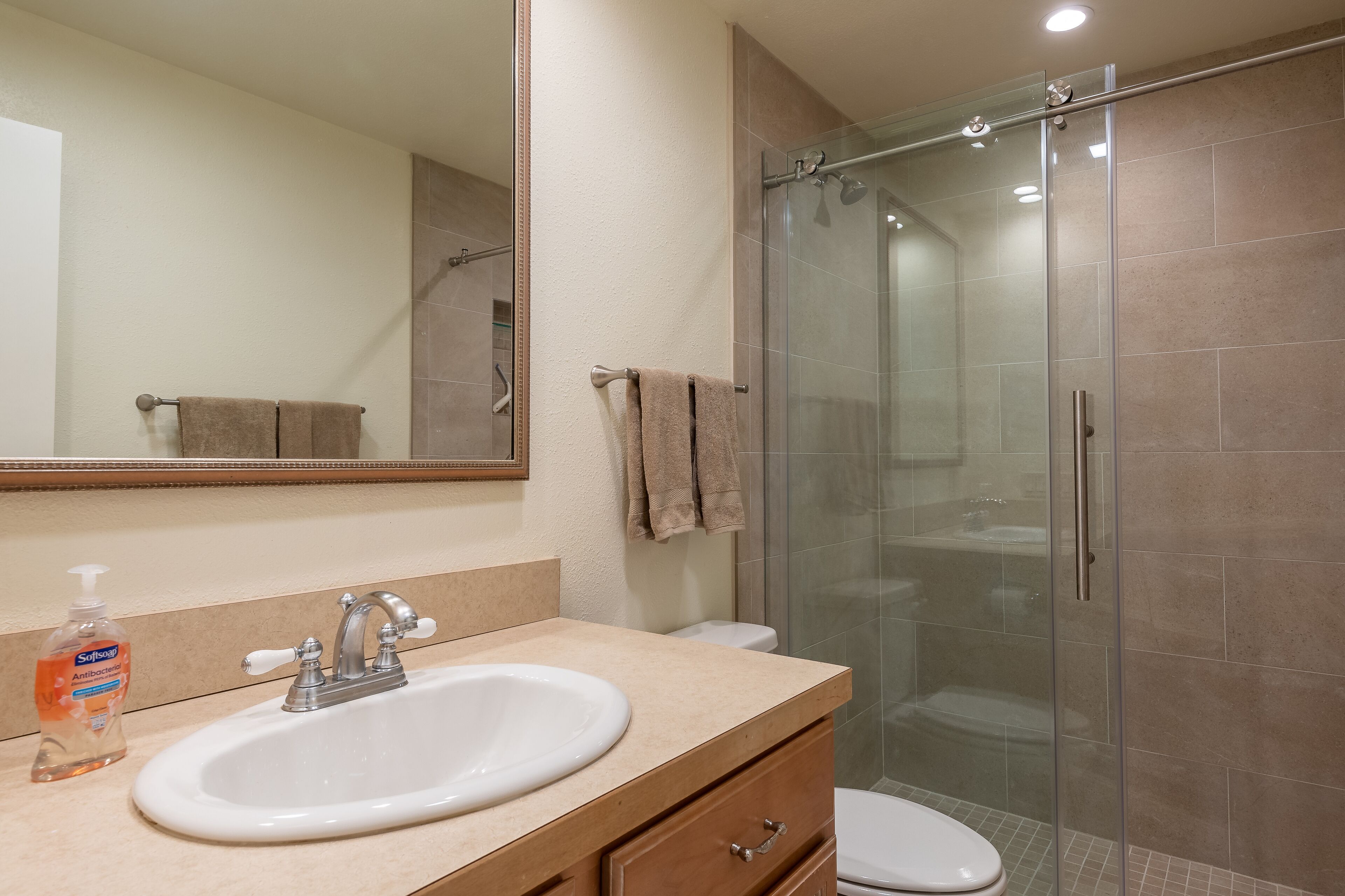 A bathroom with a sink, mirror, and glass shower enclosure.