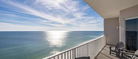 Een balkon met uitzicht op de oceaan, een tafel en twee stoelen.