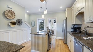A kitchen with a central island, wooden flooring, white cabinetry, and a ceiling fan. - Glamorous Sunsets With THIS Westward View Of Undeveloped Park On Intracoastal (Pensacola)