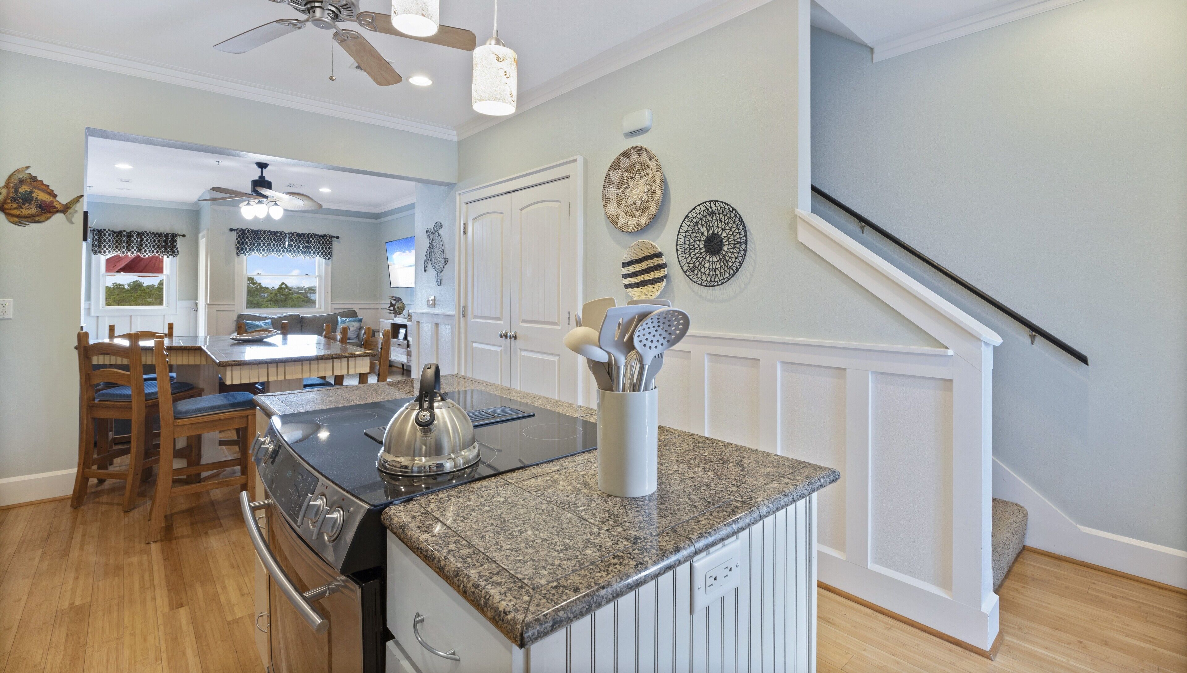A kitchen with granite countertops, a built-in oven, and a dining area with wooden chairs and a table.