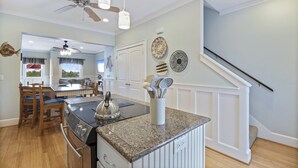 A kitchen with granite countertops, a built-in oven, and a dining area with wooden chairs and a table. - Glamorous Sunsets With THIS Westward View Of Undeveloped Park On Intracoastal (Pensacola)