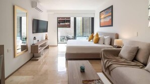 A modern living room with a large bed, a sofa, a coffee table, and a TV. - Apartments near 5th Avenue with Rooftop Ocean View (Playa del Carmen)
