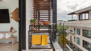 A modern balcony with a wooden slatted design, potted plants, and a yellow towel. - Apartments near 5th Avenue with Rooftop Ocean View (Playa del Carmen)