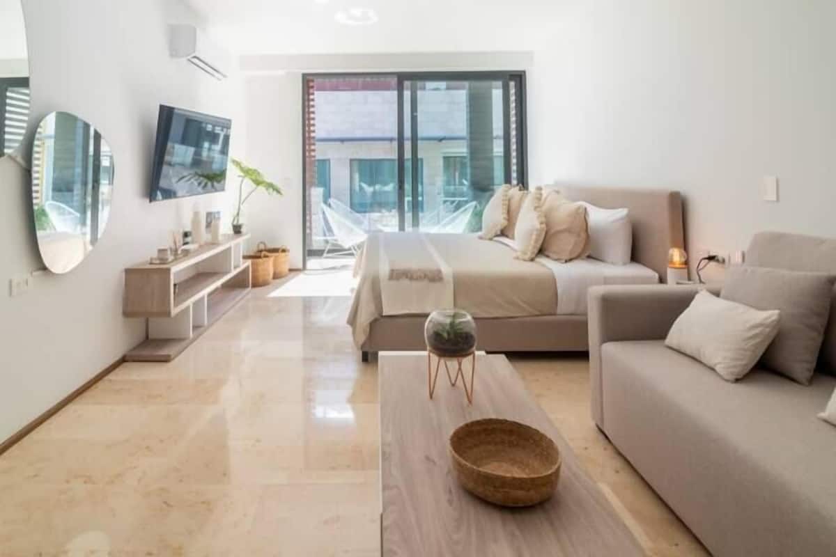 A modern living room with a sofa, a coffee table, and a TV mounted on the wall.