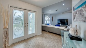 A modern living room with a glass coffee table, a flat-screen TV, and a decorative vase. - New to VRBO, Pelican Way, Heated Private Pool, Large Lanai area, Billiards..... (Cape Coral)