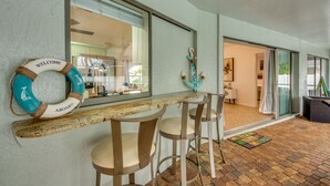 A bar area with a wooden counter and two bar stools, a lifebuoy with 'WELCOME ABOARD' text, and a view into the room. - New to VRBO, Pelican Way, Heated Private Pool, Large Lanai area, Billiards..... (Cape Coral)