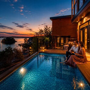 A poolside area with a view of a body of water and a sunset.