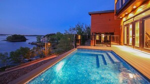 Un hotel moderno con piscina, terraza de madera y vista al agua.