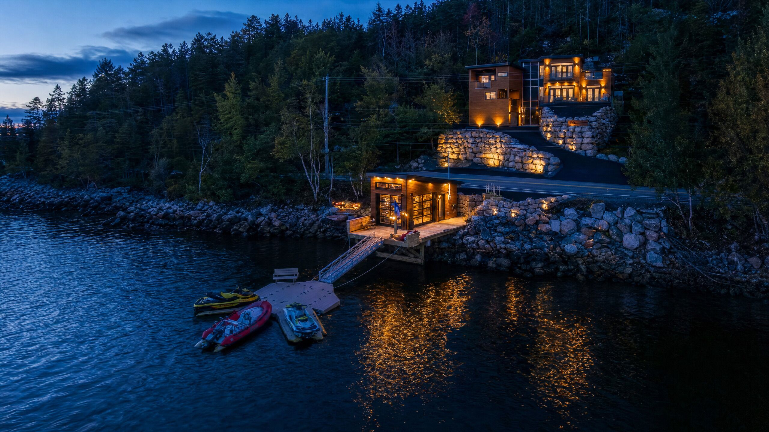 A waterfront property with a dock, a stone wall, and a modern building with multiple levels.