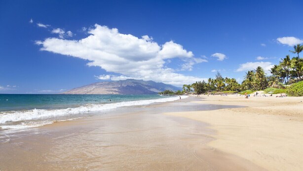 A beach with clear skies, calm waters, and a mountain in the background. - Luxury Condo at Kameole Beach (Kihei)