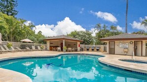 A swimming pool with lounge chairs and a covered area, surrounded by trees and a clear sky. - Luxury Condo at Kameole Beach (Kihei)