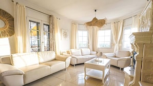 A spacious living room with a beige sofa set, a coffee table, and a decorative hanging light fixture.