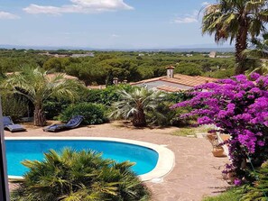 A pool surrounded by lush greenery and a view of distant buildings. - Spectacular sea and mountain views, private pool, Wifi, PMR access (L'Escala)