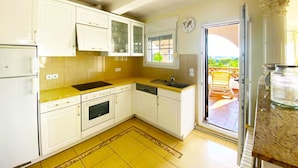 A compact kitchen with white cabinets, a built-in oven, and a sink.