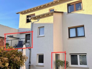 Een meerlaags gebouw met een balkon, ramen en een duidelijke deur.