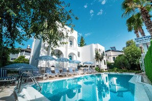 A swimming pool with lounge chairs and umbrellas, a white building with arched windows, and a sign for KemerRoyce Beach Hotel. - Kemer Royal Beach Hotel (Kemer)