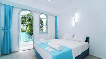 A hotel room with a bed, a window, and a view of greenery outside.