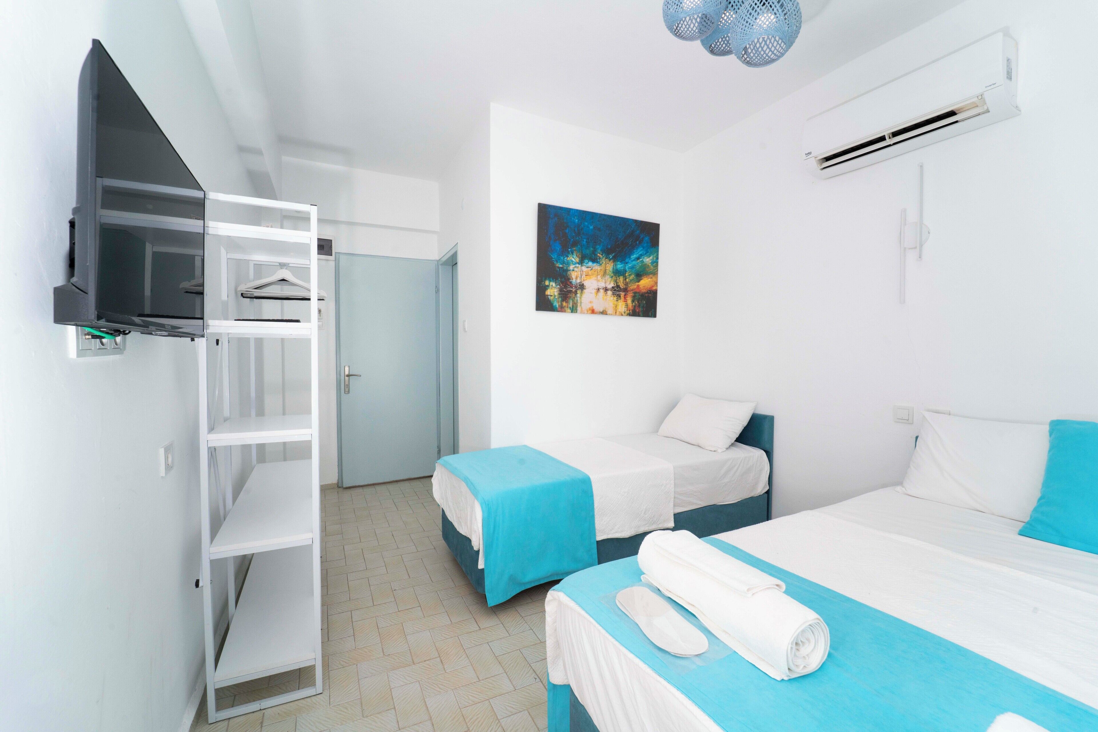 Habitación de hotel con dos camas, un armario, un cuadro y un equipo de aire acondicionado.