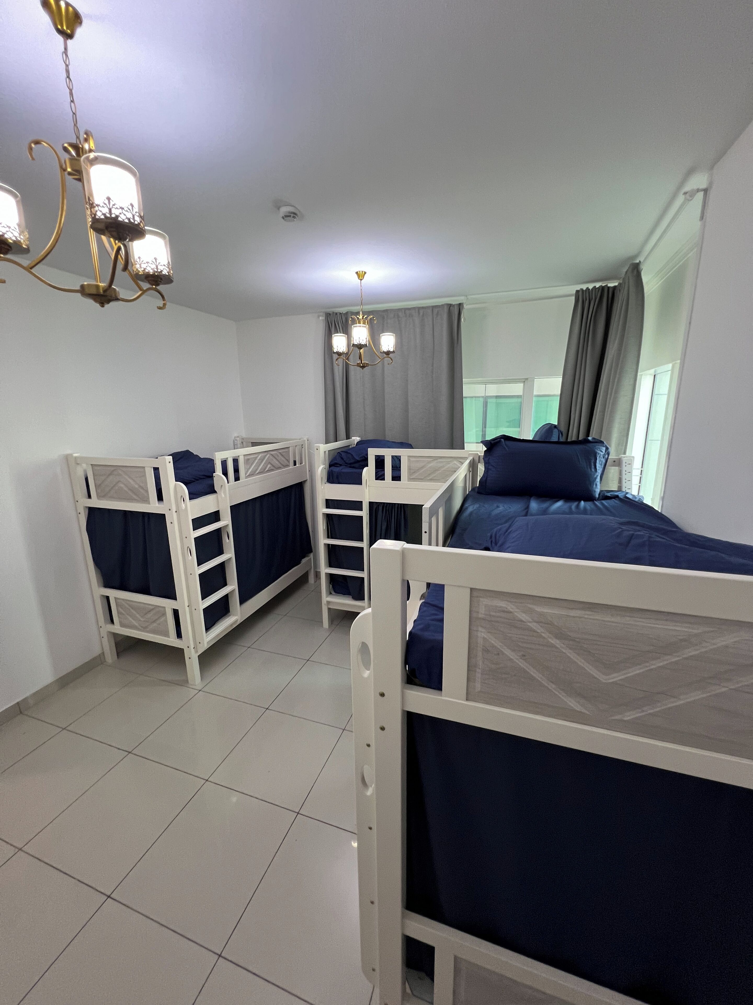 Ein Zimmer mit Etagenbetten, einem Kronleuchter und einem Vorhangfenster.