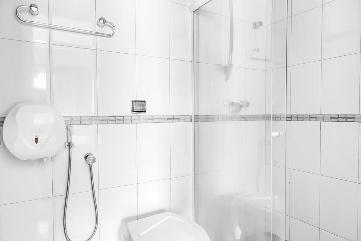 Un baño moderno con cabina de ducha de vidrio, ducha de mano y un inodoro.