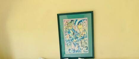 Een hotelkamer met een bed, een plafondventilator, een ingelijst kunstwerk aan de muur en twee bedlampen.
