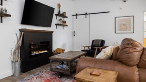 Ein modernes Wohnzimmer mit Kamin, Flachbildfernseher, Sofa und Couchtisch.