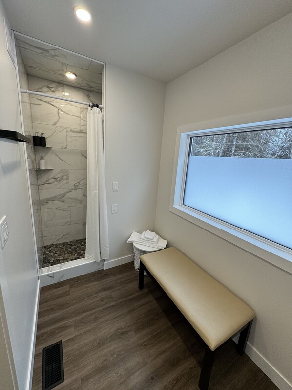 Une salle de bain avec une douche, un banc et une fenêtre.
