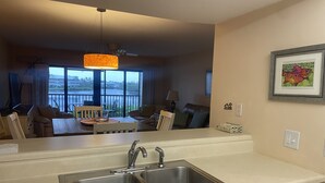 A modern kitchen with a double sink, a dining area with a table and chairs, and a view of the outdoors through large windows. - 2/2.5 Waterfront condo with pools and tennis courts (Bokeelia)