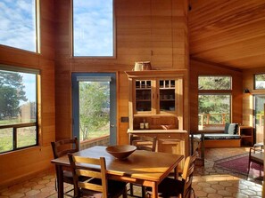 A spacious room with a large dining table, wooden cabinets, and a view of the outdoors.