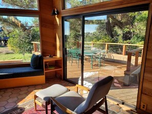 A modern interior with a seating area, a wooden deck, and a glass door leading to an outdoor space.