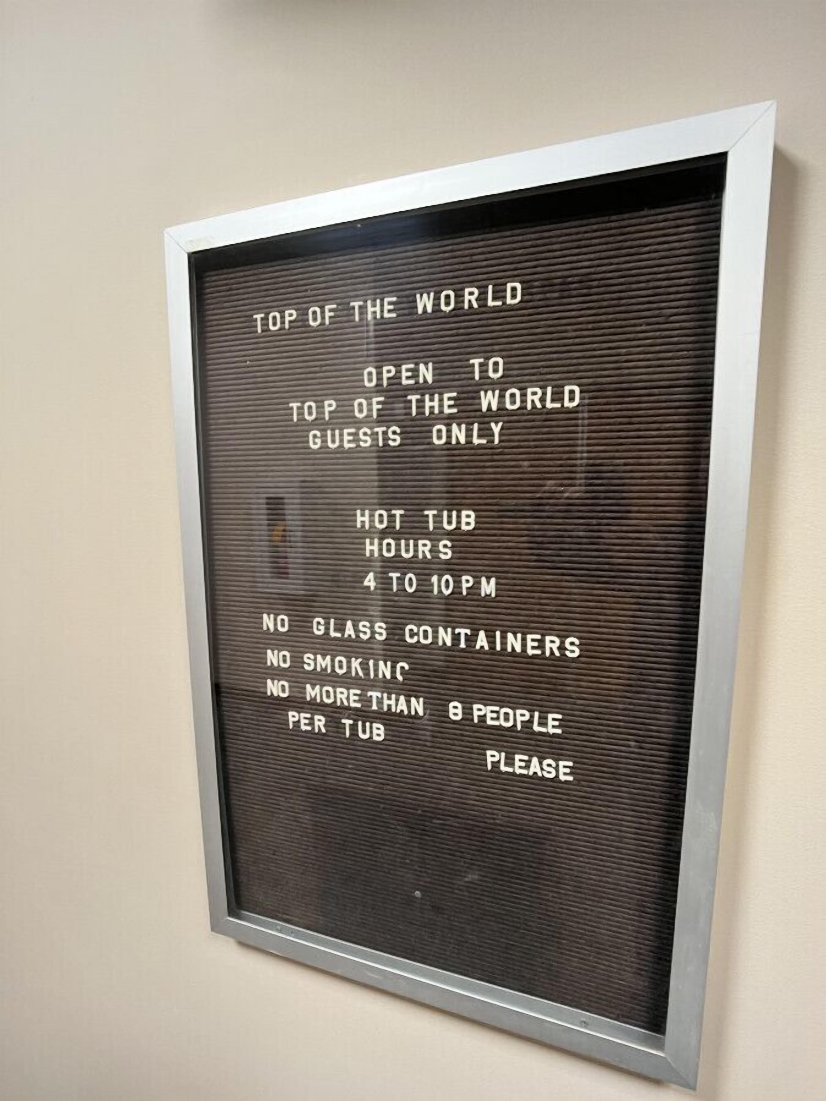 A sign with rules for a hot tub area, including hours of operation and guest limits.