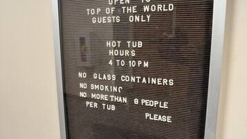 A sign with rules for a hot tub area, including hours of operation and guest limits.
